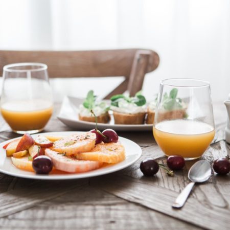 A photo of a table with glasses of fruit juice and plates of fresh fruit