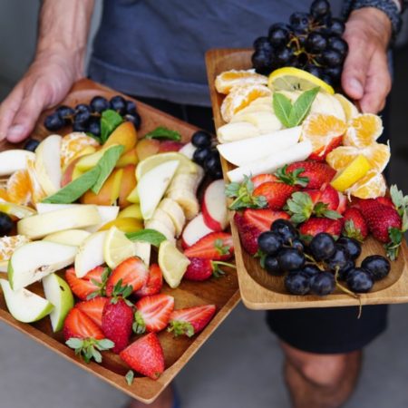 A photo of someone carrying platters of fresh fruit.