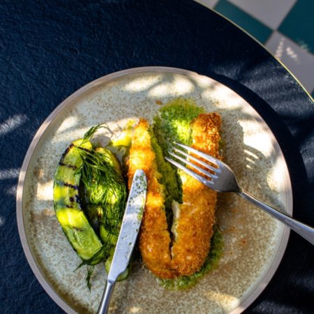 A photo of a plate of food taken from above. It looks like courgette, green vegetables and breaded fish