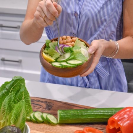 A photo of a woman seasoning a bowl of vegetables
