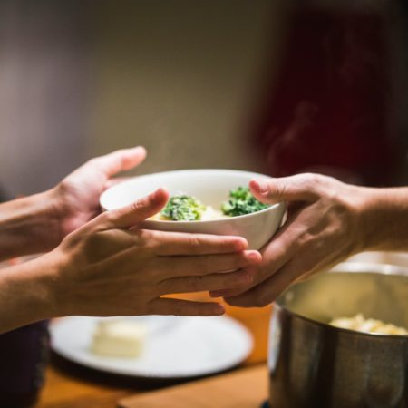 Close photo of two people holding a bowl of food